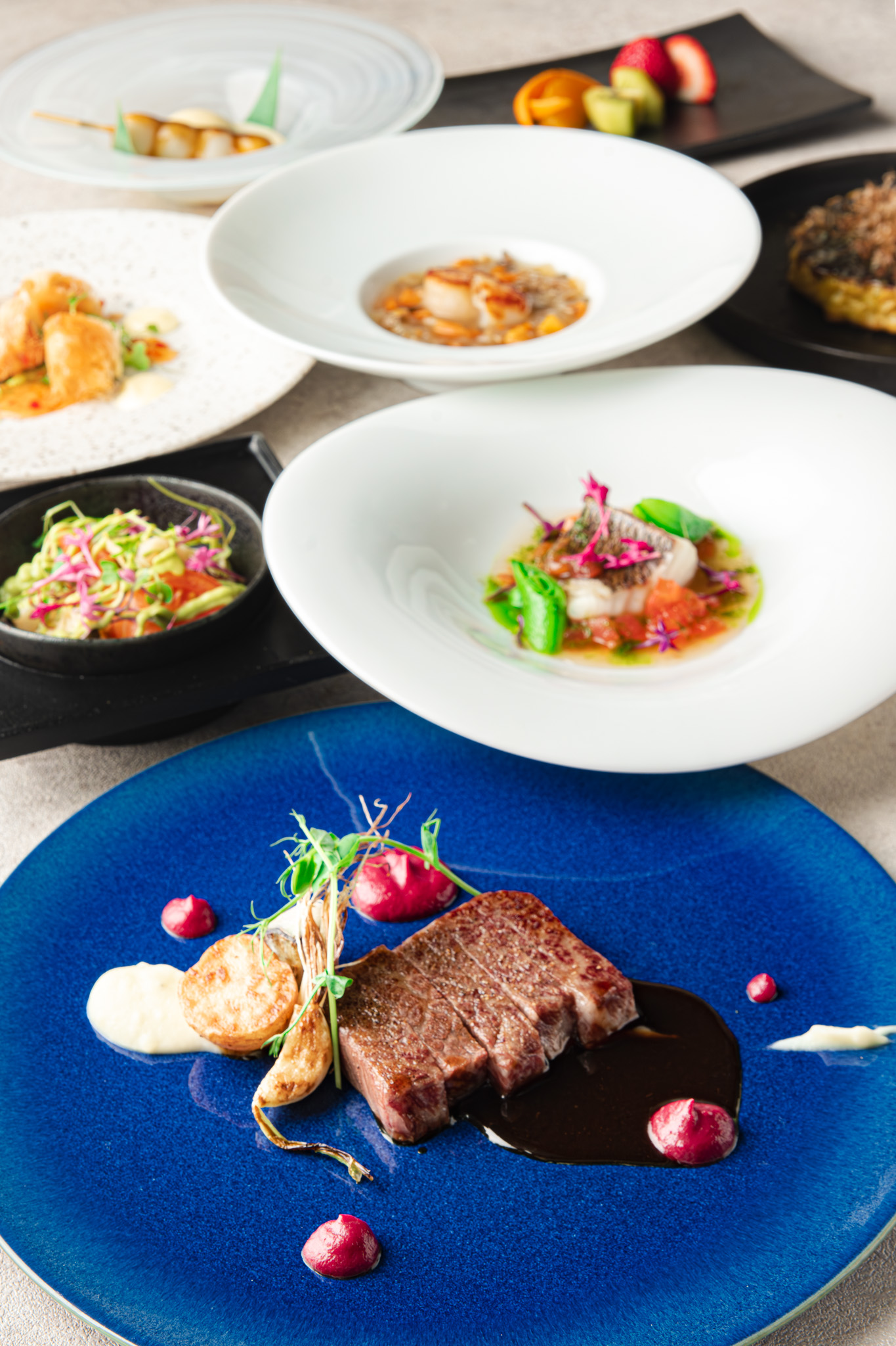Multi-course lunch spread with blue steak plate